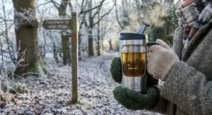 Person holding a travel mug with built-in infuser while enjoying herbal tea on a brisk winter walk