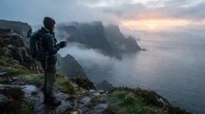 A hiker holding one of the top camping mugs under £20 while overlooking a misty cliffside trail on a crisp morning